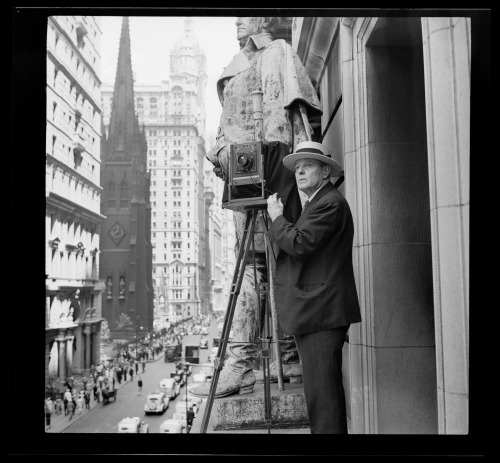 Wurts Bros. (New York, N.Y.) Broadway and Exchange Place. Norman Wurts making photos from 4th-story ledge on Exchange Court Building, 1937. Museum of the City of New York. X2010.7.1.8427