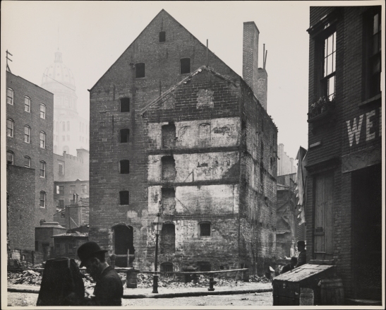 View of the Rhinelander Sugar House at the corner of Rose Street and Duane Street after a fire  Another photographer is visible in the foreground.