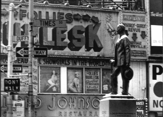 View of Times Square at Broadway and W. 46th Street and of the Father Duffy Statue in front of Howard Johnson's Restaurant in 1967.  Signs above the Howard Johnson's say "[M]os[t] Beau[tifu]l Showgirls in the World", and "All Live Whirly=Girly Revue plus BigTime VaudeVille."